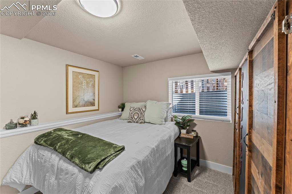Carpeted bedroom with a textured ceiling and baseboards