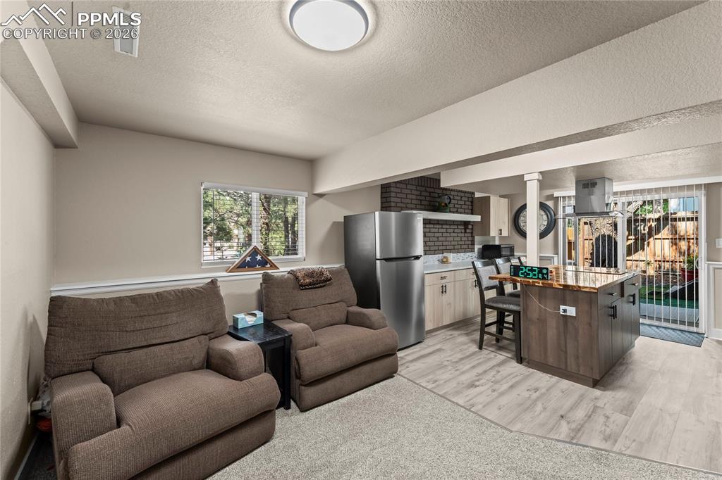 Living area in apartment with light wood-style flooring and a textured ceiling