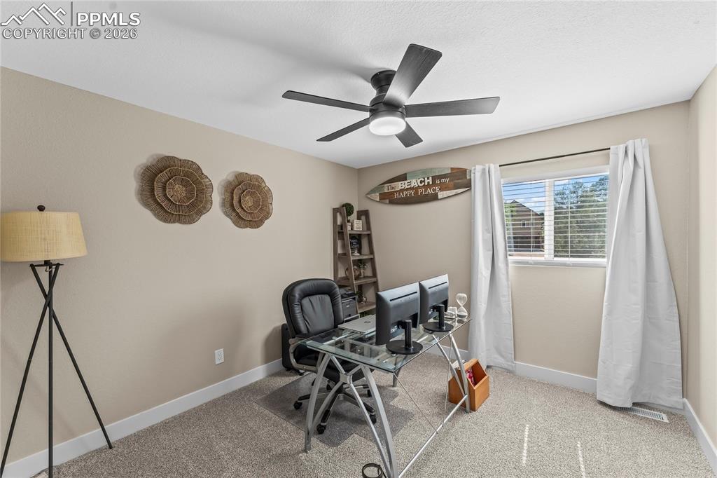Carpeted office space with baseboards and ceiling fan