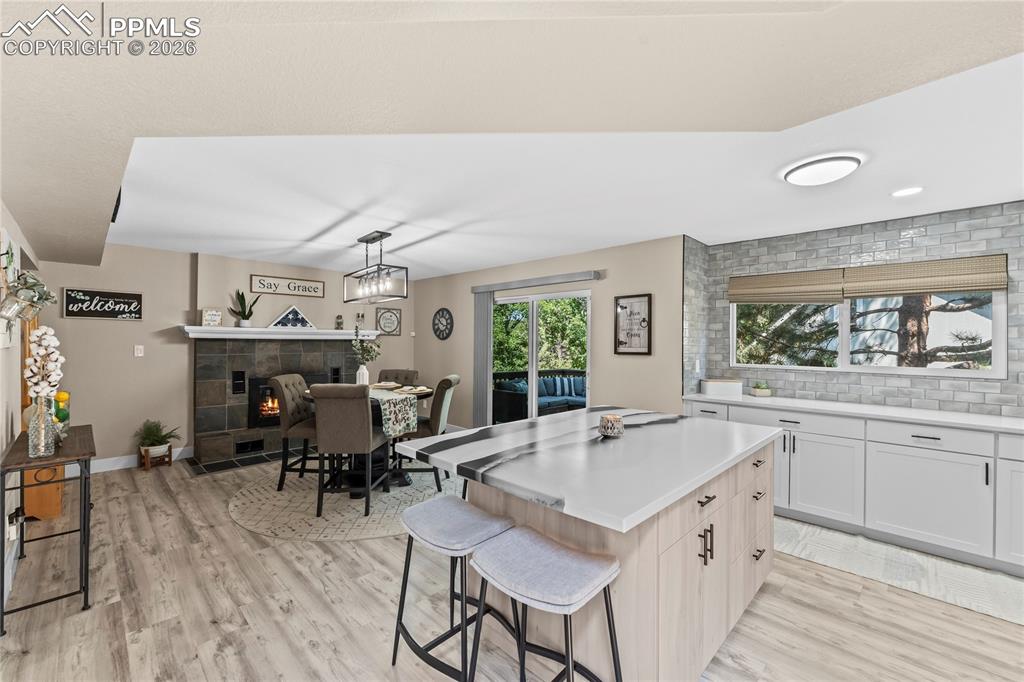 Kitchen featuring a tiled fireplace, a kitchen island, light countertops, and healthy amount of natural light
