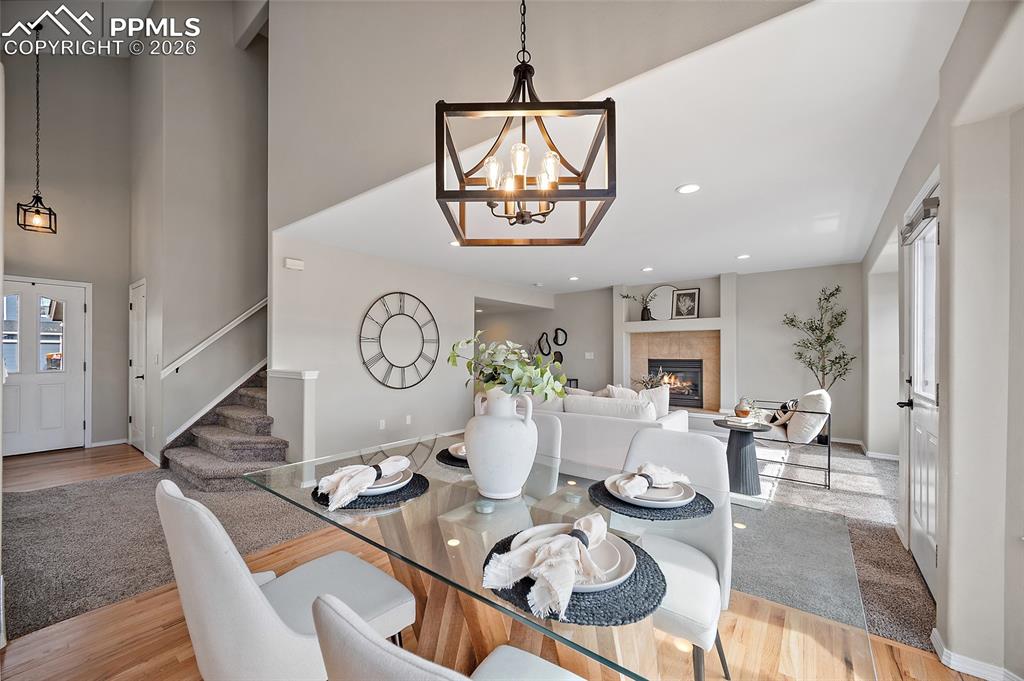 Dining area with light wood-style floors, hanging lights, a tile fireplace, and healthy amount of natural light