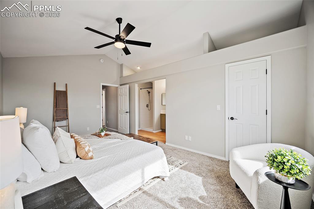 Bedroom featuring lofted ceiling, light carpet, a ceiling fan, and connected bathroom