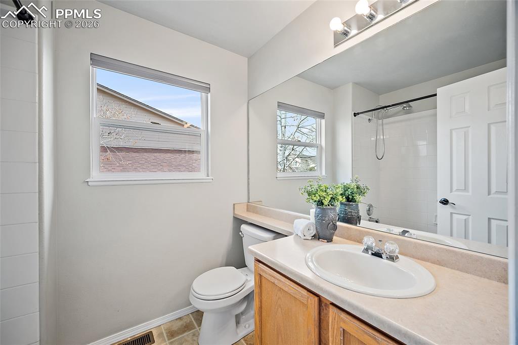 Bathroom with vanity, a shower, and light tile patterned flooring