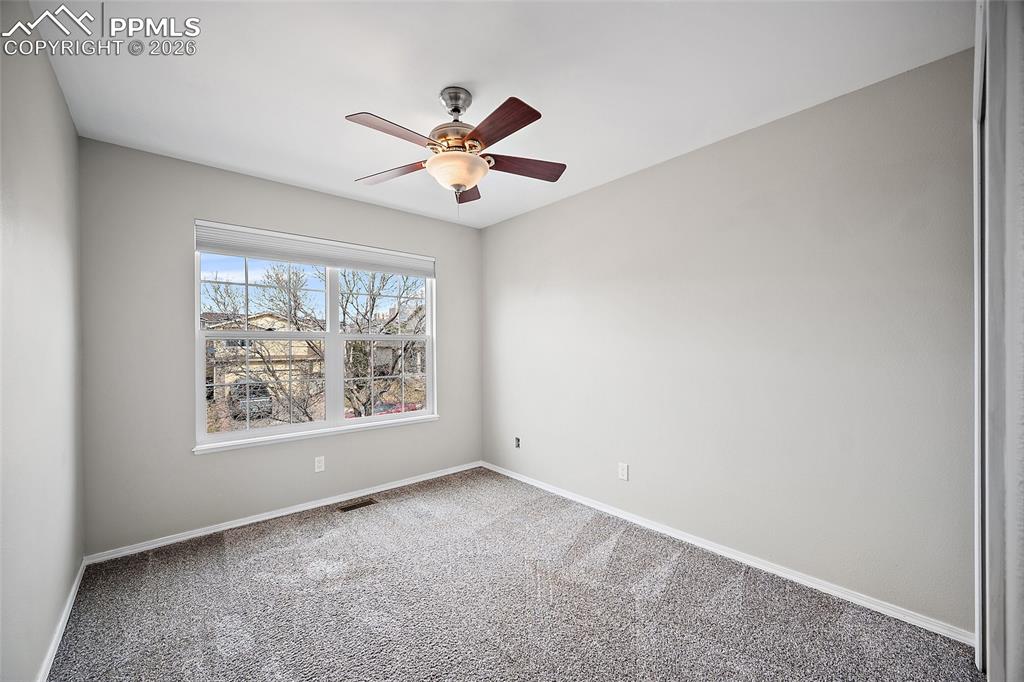 Empty room featuring light carpet and a ceiling fan