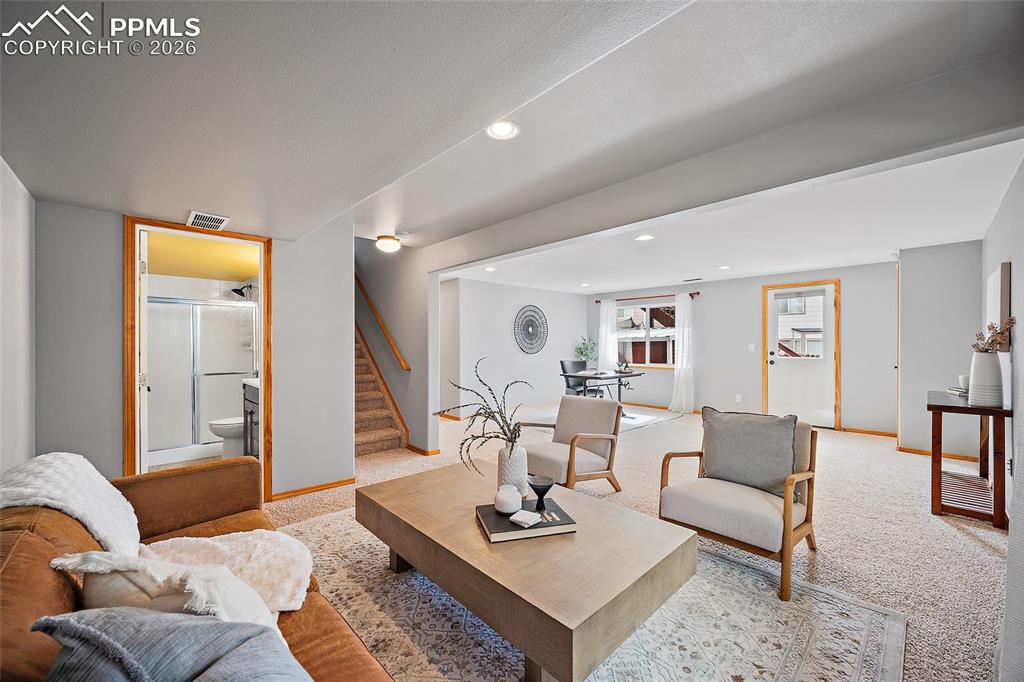 Living area with light carpet and recessed lighting