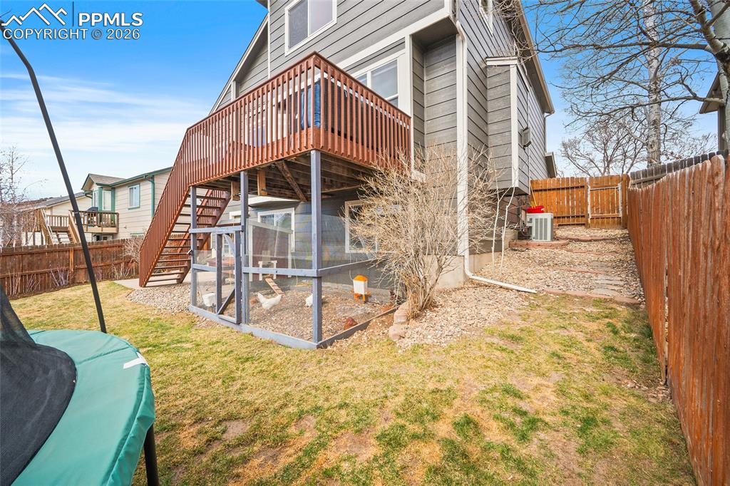 Back of house featuring a trampoline, a fenced backyard, a sunroom, and a deck