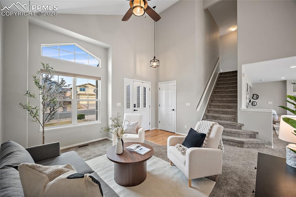 Living room featuring ceiling fan, vaulted ceiling, and light wood-style floors