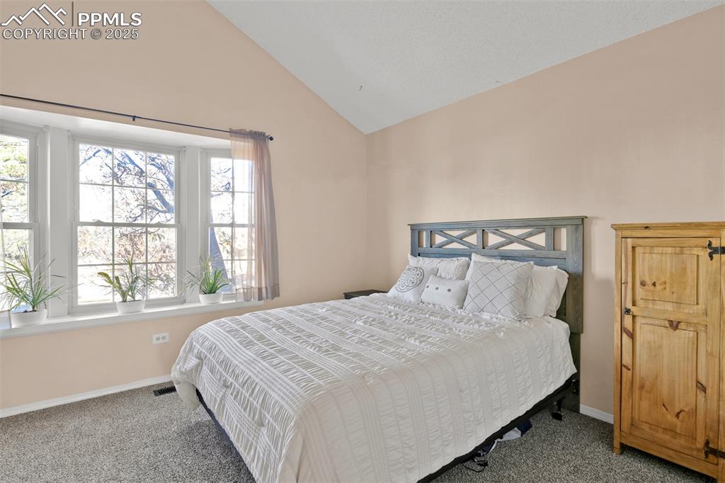 Carpeted bedroom 1 on the upper level with adjacent 3/4 bath featuring high vaulted ceiling