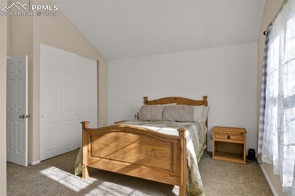 Bedroom 2 on upper level featuring carpet, a closet, and lofted ceiling