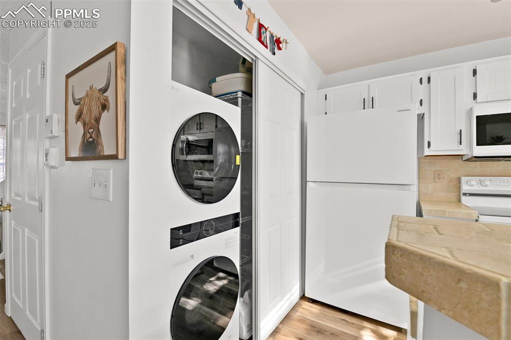 Laundry room featuring light wood finished floors and stacked washer and clothes dryer