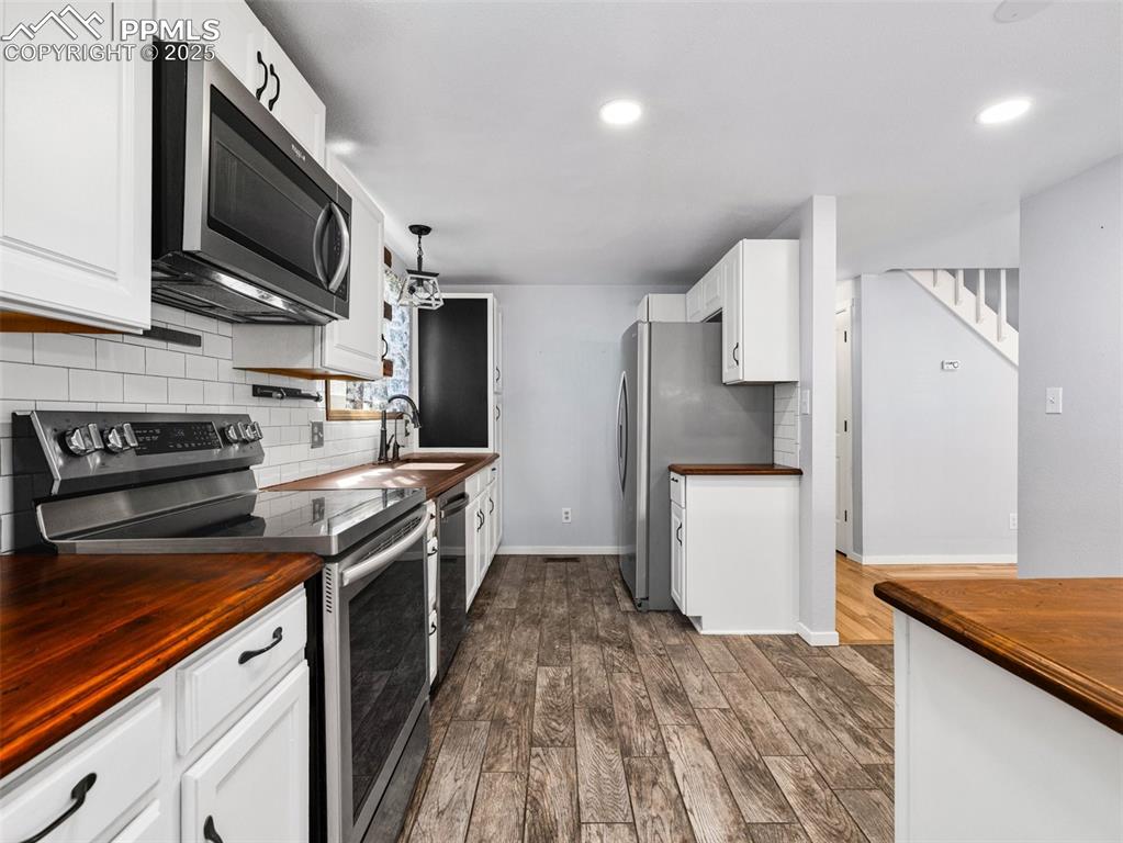 Kitchen featuring stainless steel appliances, butcher block counters, white cabinetry, and recessed lighting