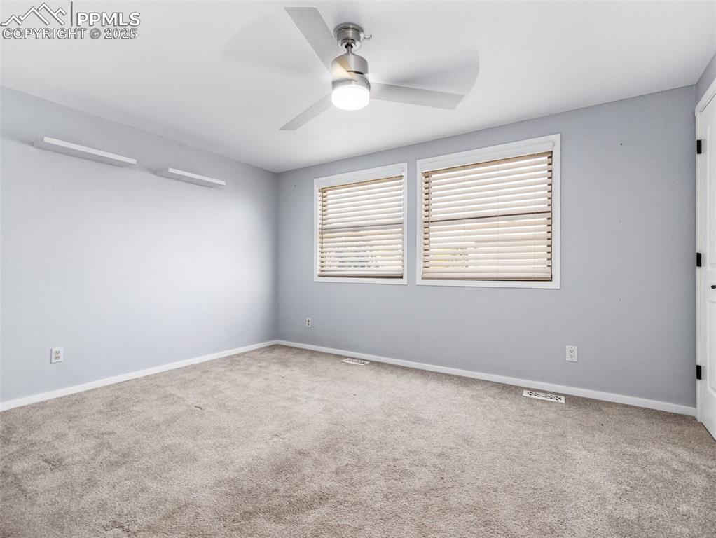 Empty room featuring light colored carpet and ceiling fan