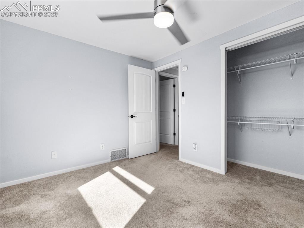 Unfurnished bedroom with light colored carpet, a closet, and a ceiling fan