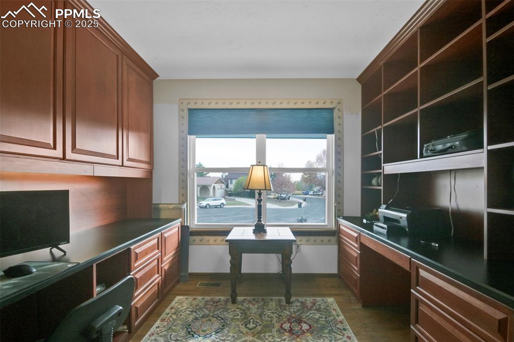 Home office featuring built in desk and dark wood-type flooring