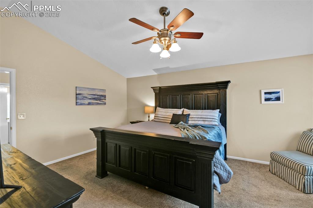 Bedroom with lofted ceiling, light carpet, and ceiling fan