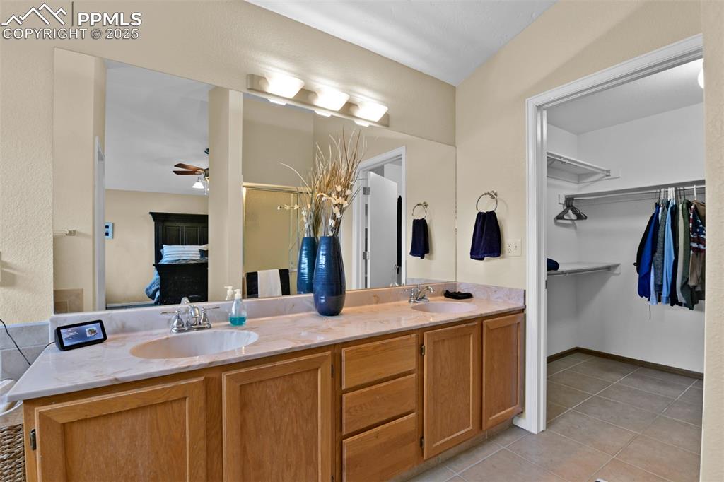 Full bath featuring light tile patterned floors, double vanity, and a ceiling fan