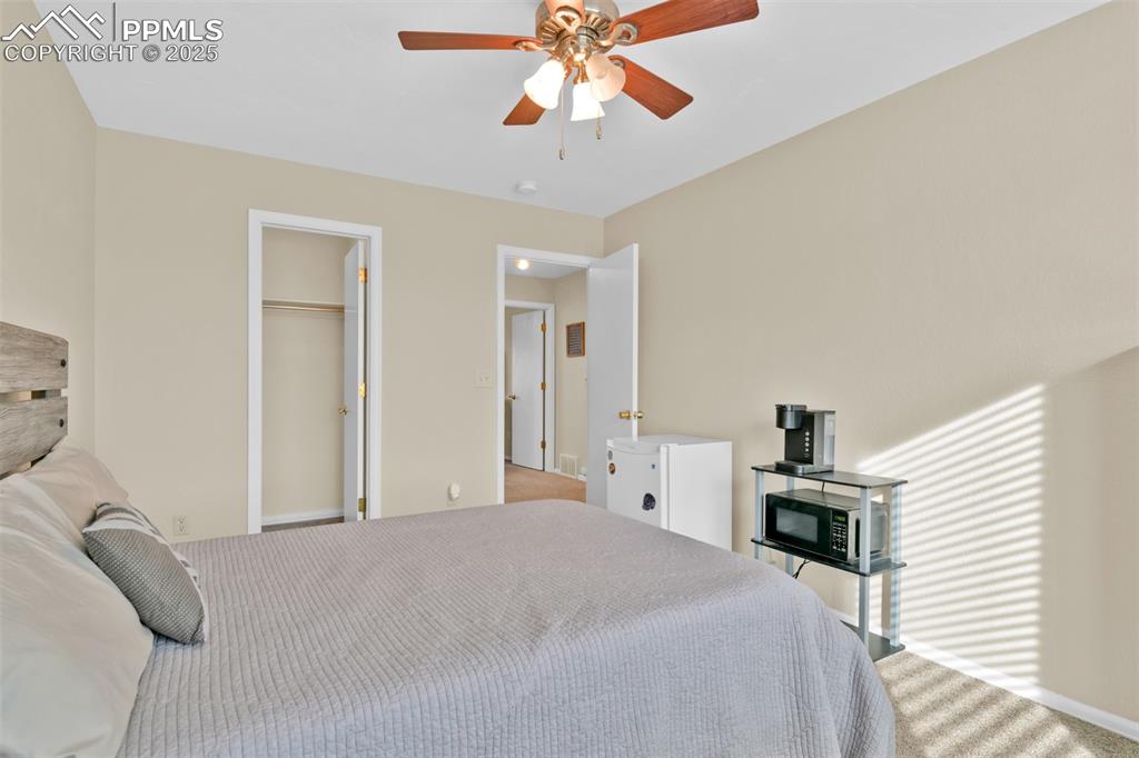 Carpeted bedroom with ceiling fan and a spacious closet
