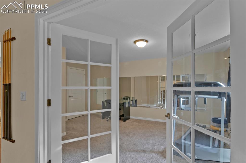 Walk in closet with french doors and light colored carpet