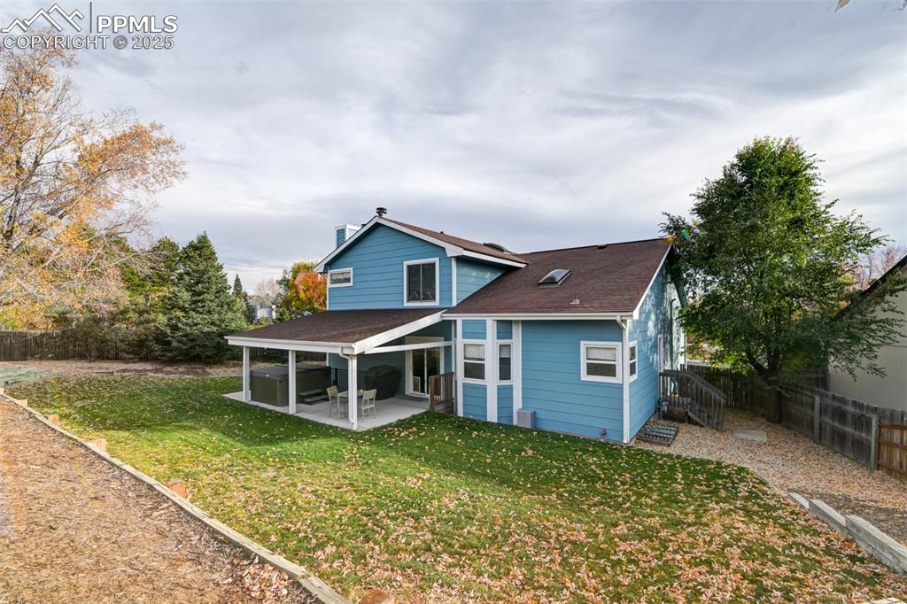 Rear view of property with a fenced backyard, roof with shingles, and a patio