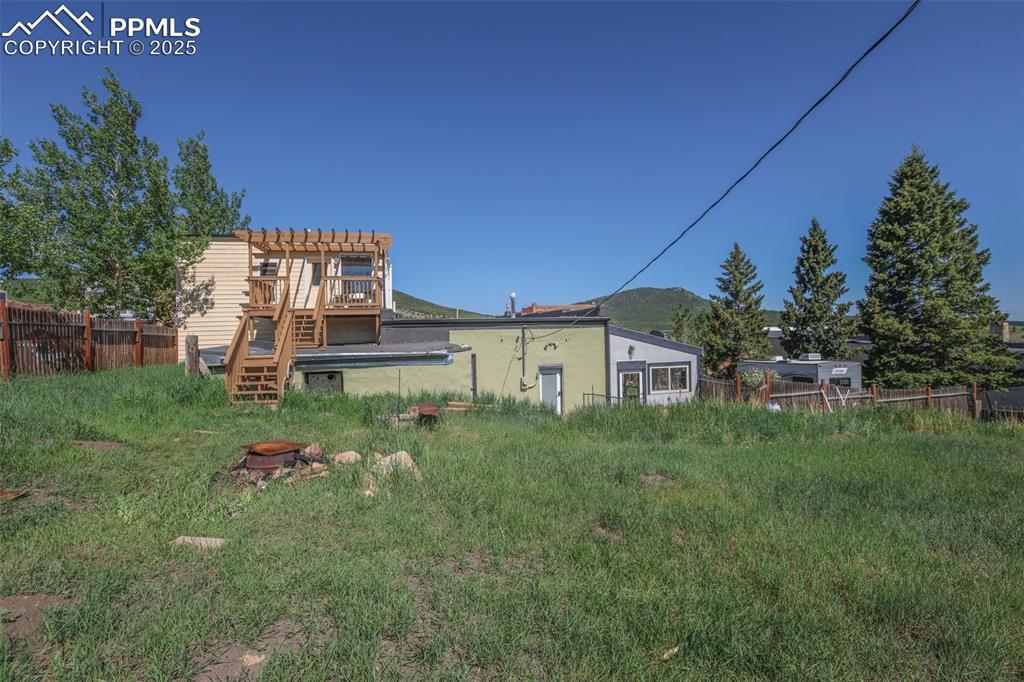 from the yard, looking east, stairs lead to deck off of the bedroom/bath over the garage, note door out of laundry room and door out of solatium on the ground level