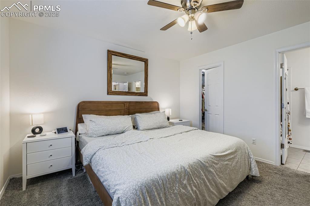 Carpeted bedroom with ceiling fan and a spacious closet