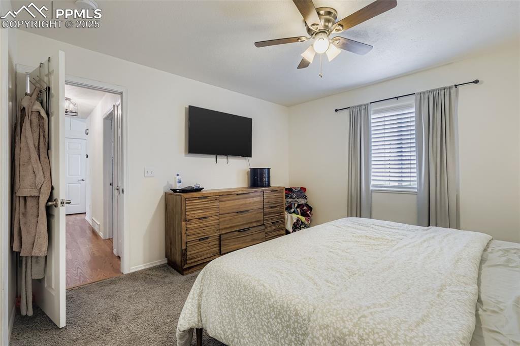 Carpeted bedroom with ceiling fan and baseboards