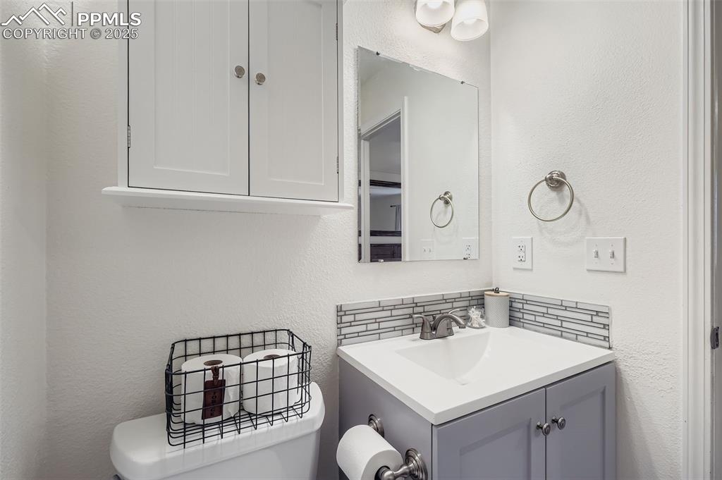 Bathroom with a textured wall, vanity, and decorative backsplash