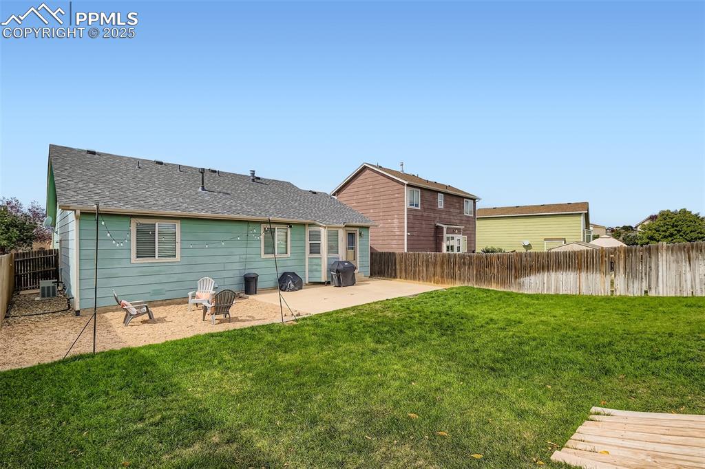 Rear view of house featuring roof with shingles, a patio area, and a fenced backyard