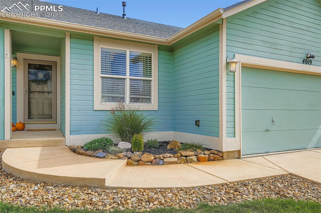 Entrance to property featuring an attached garage and a shingled roof