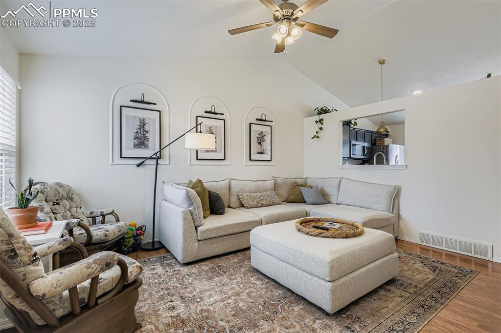 Living area with wood finished floors, a ceiling fan, and lofted ceiling