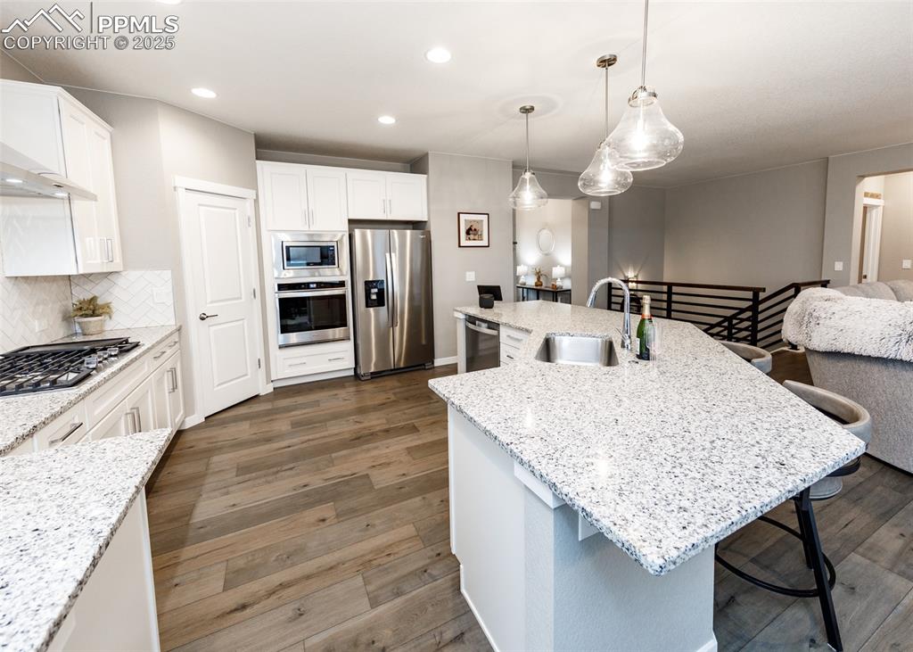 Kitchen with island, white cabinets, wood-style floors, and decorative backsplash.