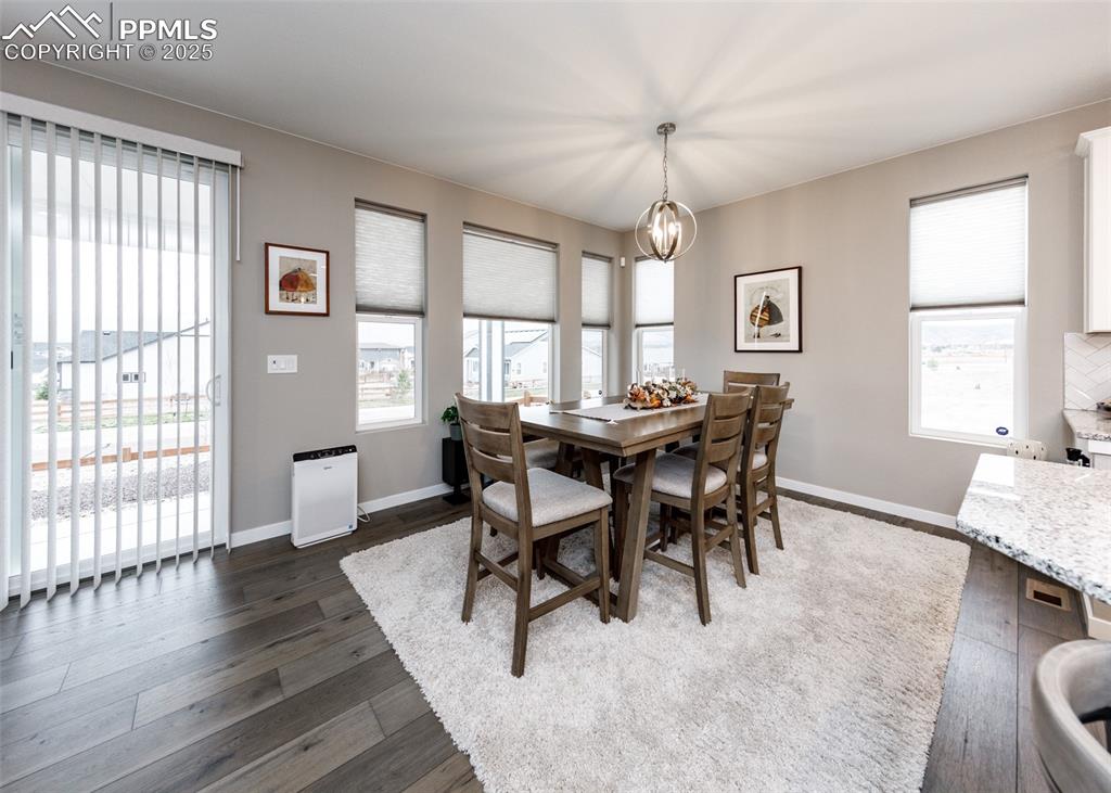 This dining room offers light wood-finished floors, a charming chandelier, ceiling fan, and a picturesque mountain view, perfect for family meals and entertaining.