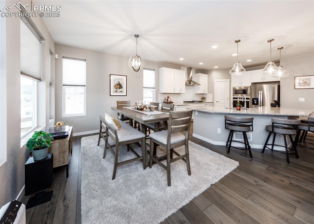 Dining room features light wood floors, a ceiling fan, chandelier, and scenic mountain views, creating a bright and inviting space.