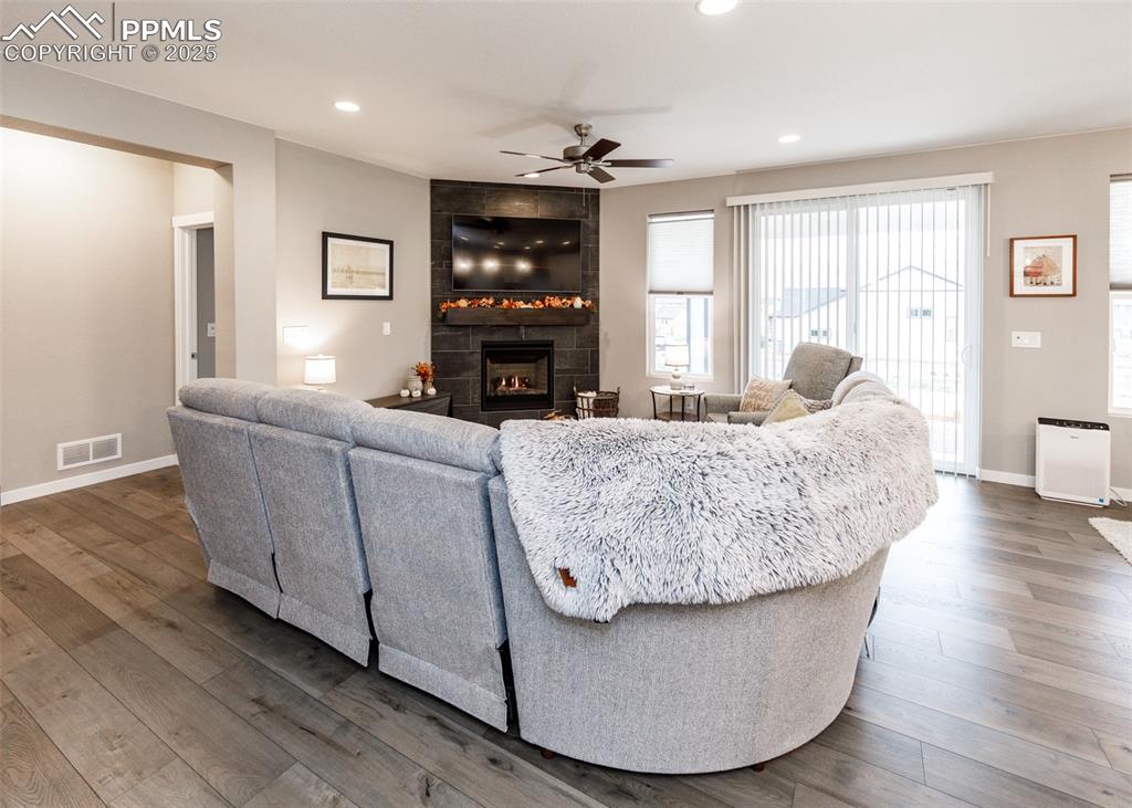 Living room features wood-finished floors, recessed lighting, a ceiling fan, and a tile fireplace.