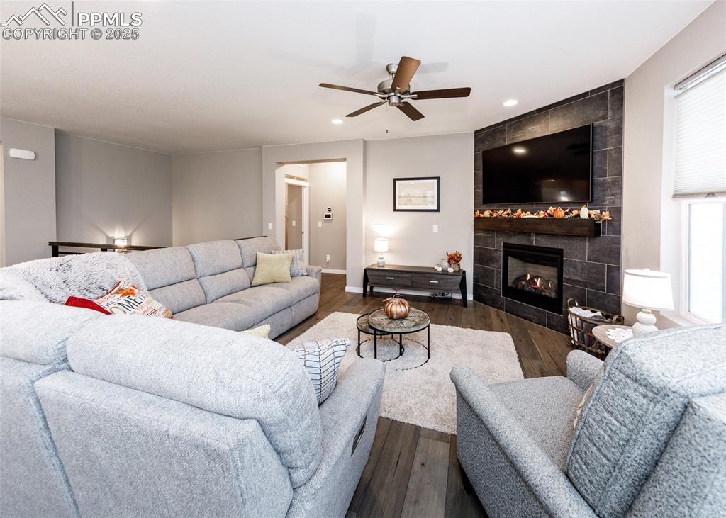 Bright living room with wood-style floors, recessed lighting, a ceiling fan, and a cozy tile fireplace.