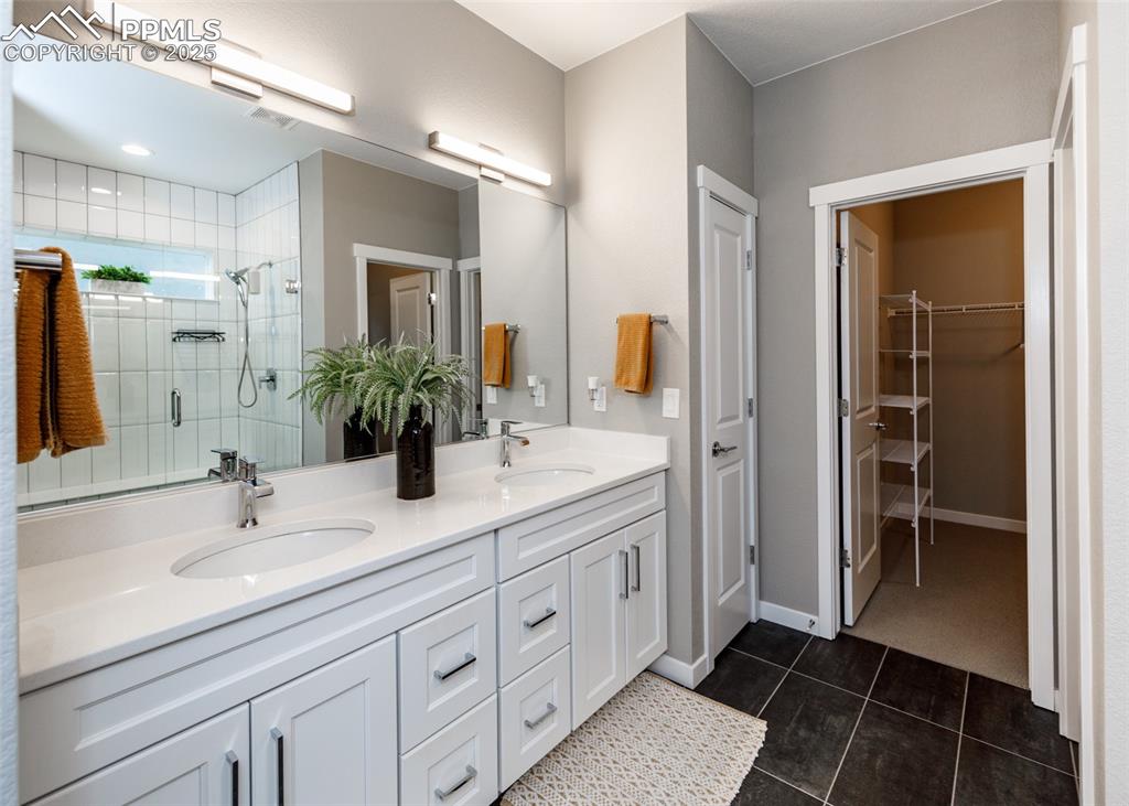 Bathroom features a double vanity, stall shower, and stylish tile-patterned flooring.