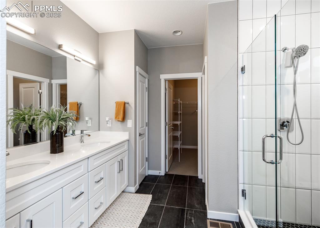 Bright bathroom with a double vanity, stall shower, and elegant tile-patterned floors.