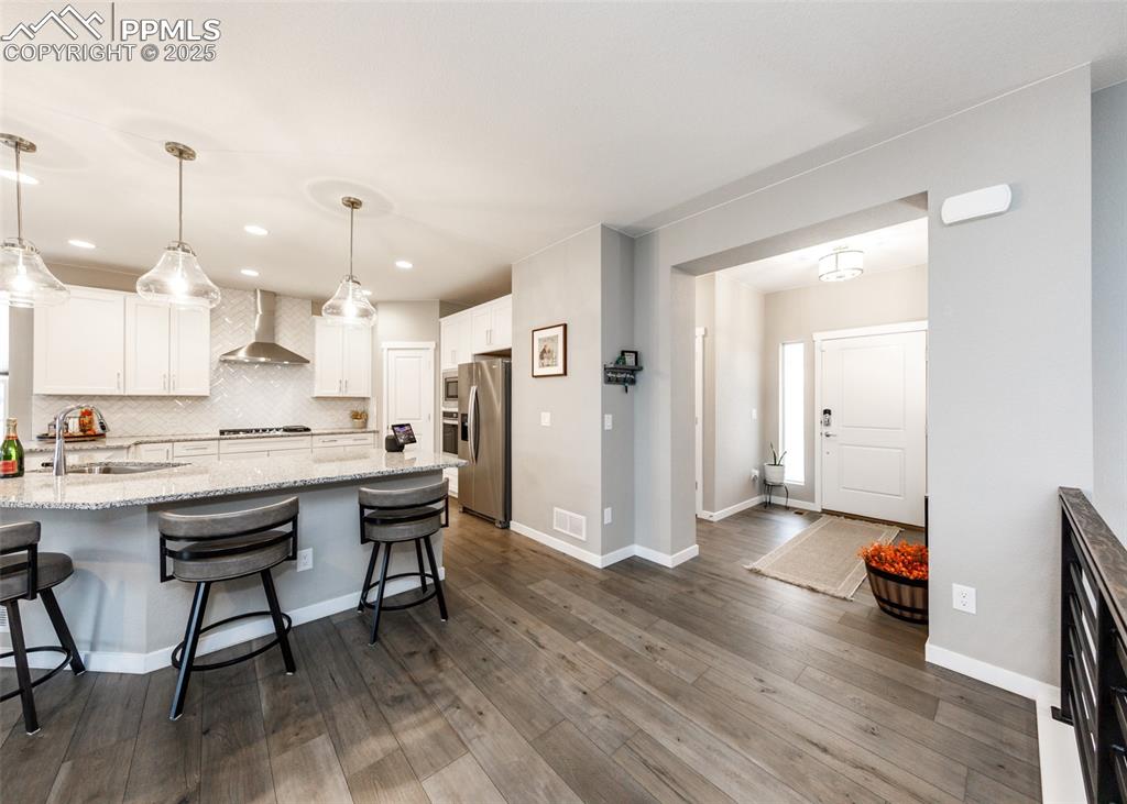 Entry into the beautiful home and kitchen with breakfast bar and elegant white cabinets.