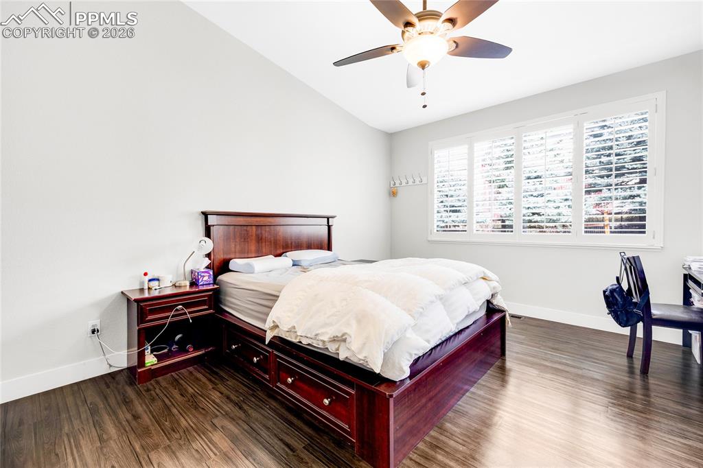 Bedroom featuring dark wood-type flooring, vaulted ceiling, and ceiling fan