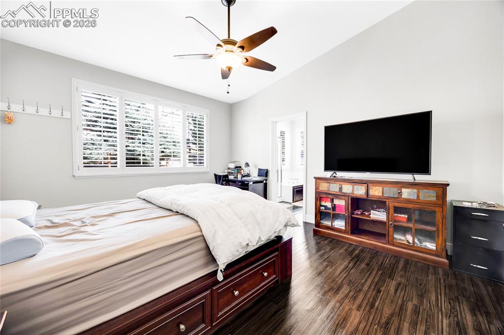 Bedroom with dark wood-type flooring, vaulted ceiling, and a ceiling fan