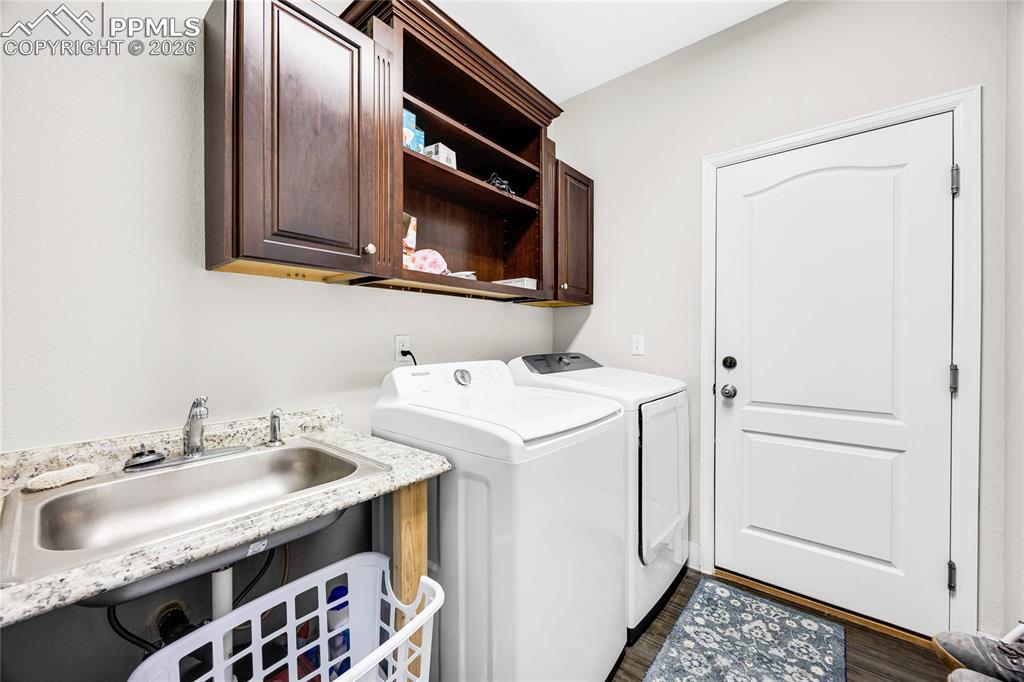 Laundry area with washer and dryer, dark wood finished floors, and cabinet space