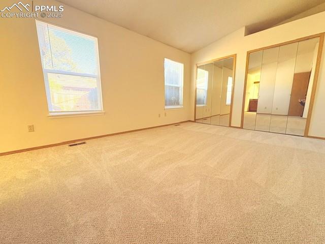 Unfurnished bedroom featuring multiple closets, carpet flooring, and vaulted ceiling