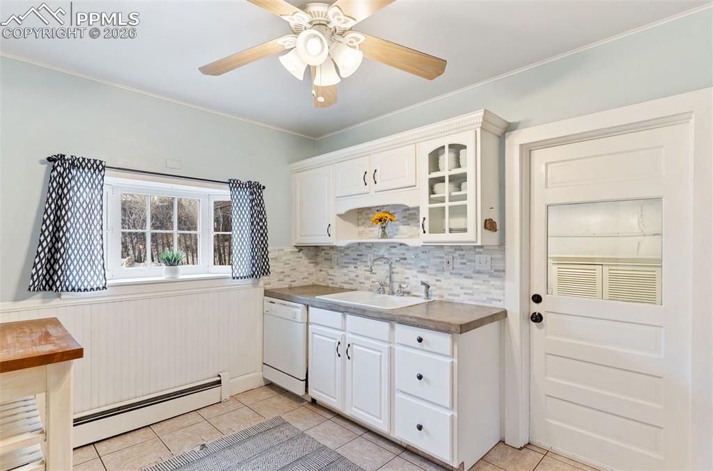 Inviting kitchen with tile floor and door that leads out to laundry, storage room, and breezeway to studio and garage.