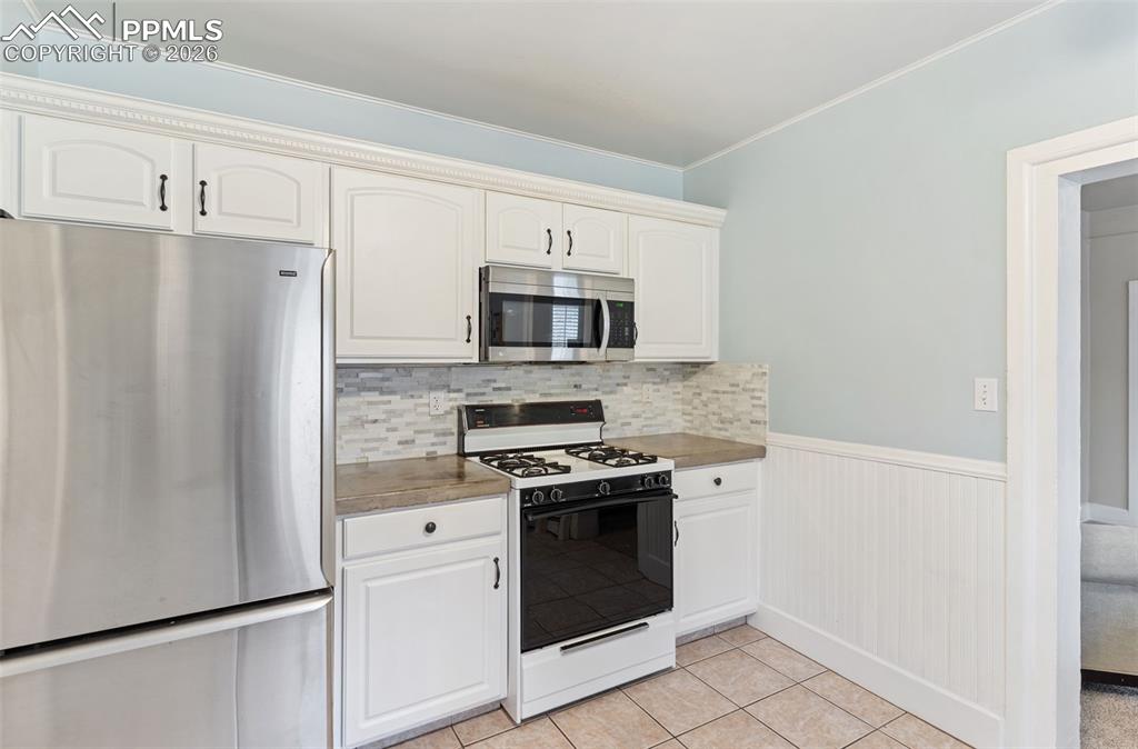 Inviting kitchen with tile floor and door that leads out to laundry, storage room, and breezeway to studio and garage.