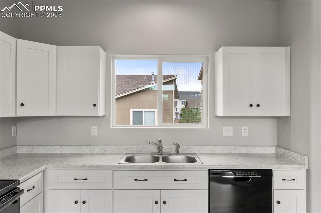 Kitchen featuring black appliances, light countertops, and white cabinets