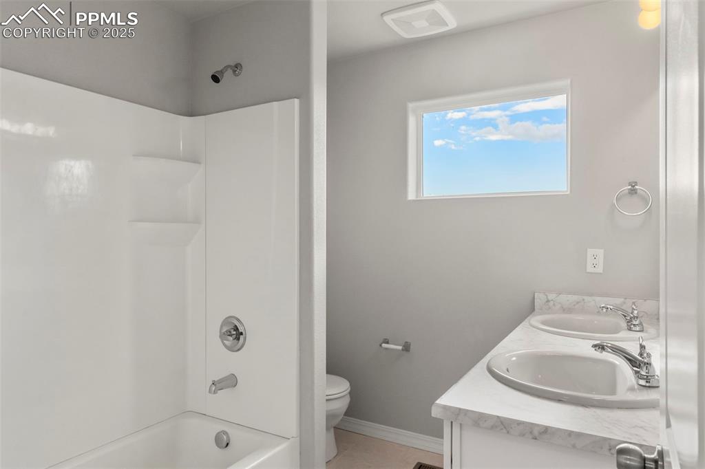 Bathroom with shower / bath combination, double vanity, and light tile patterned floors