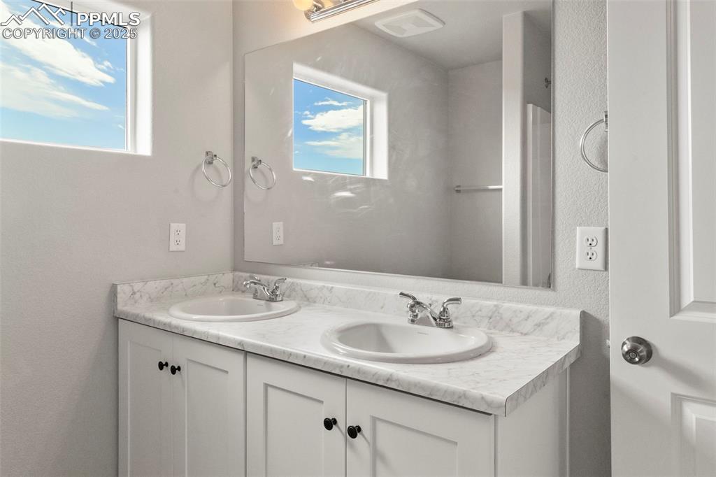 Bathroom with double vanity and a textured wall
