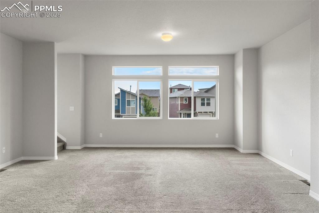Empty room with light colored carpet and baseboards