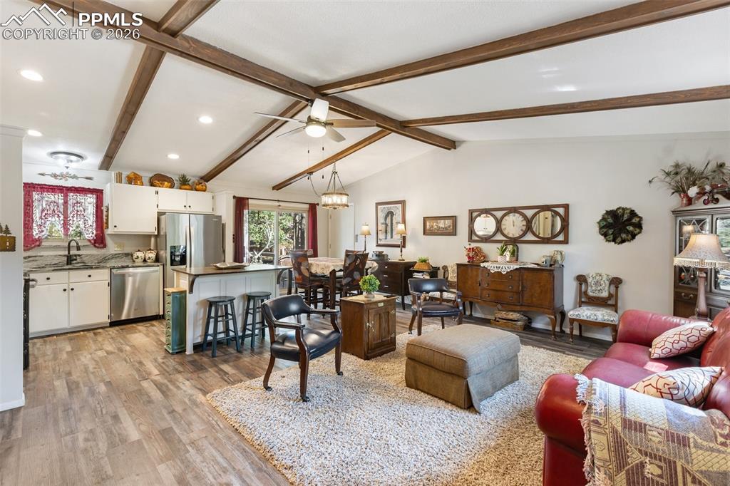 Living area with a chandelier, light wood-style flooring, and a ceiling fan