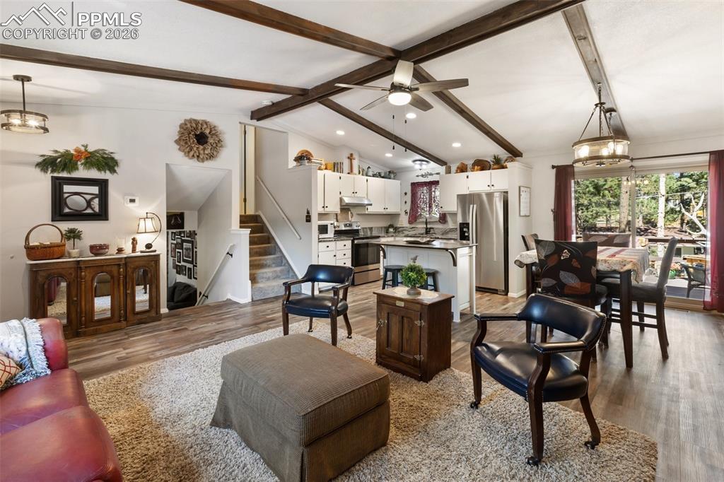 Living area featuring wood finished floors, stairs, a chandelier, and ceiling fan